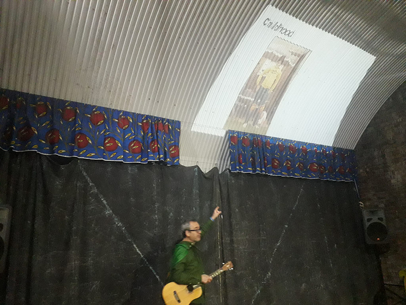 Me pointing at a slide of me on a corrugated ceiling